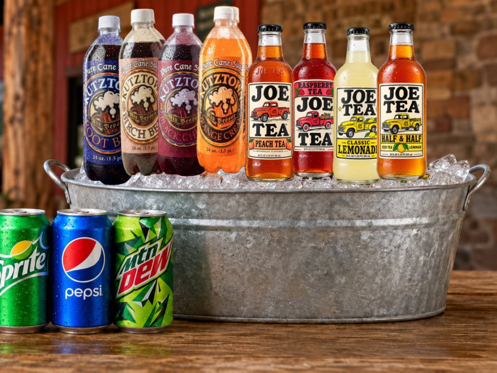 Bottled sodas and iced teas in a galvanized tub with canned soft drinks on a wooden table